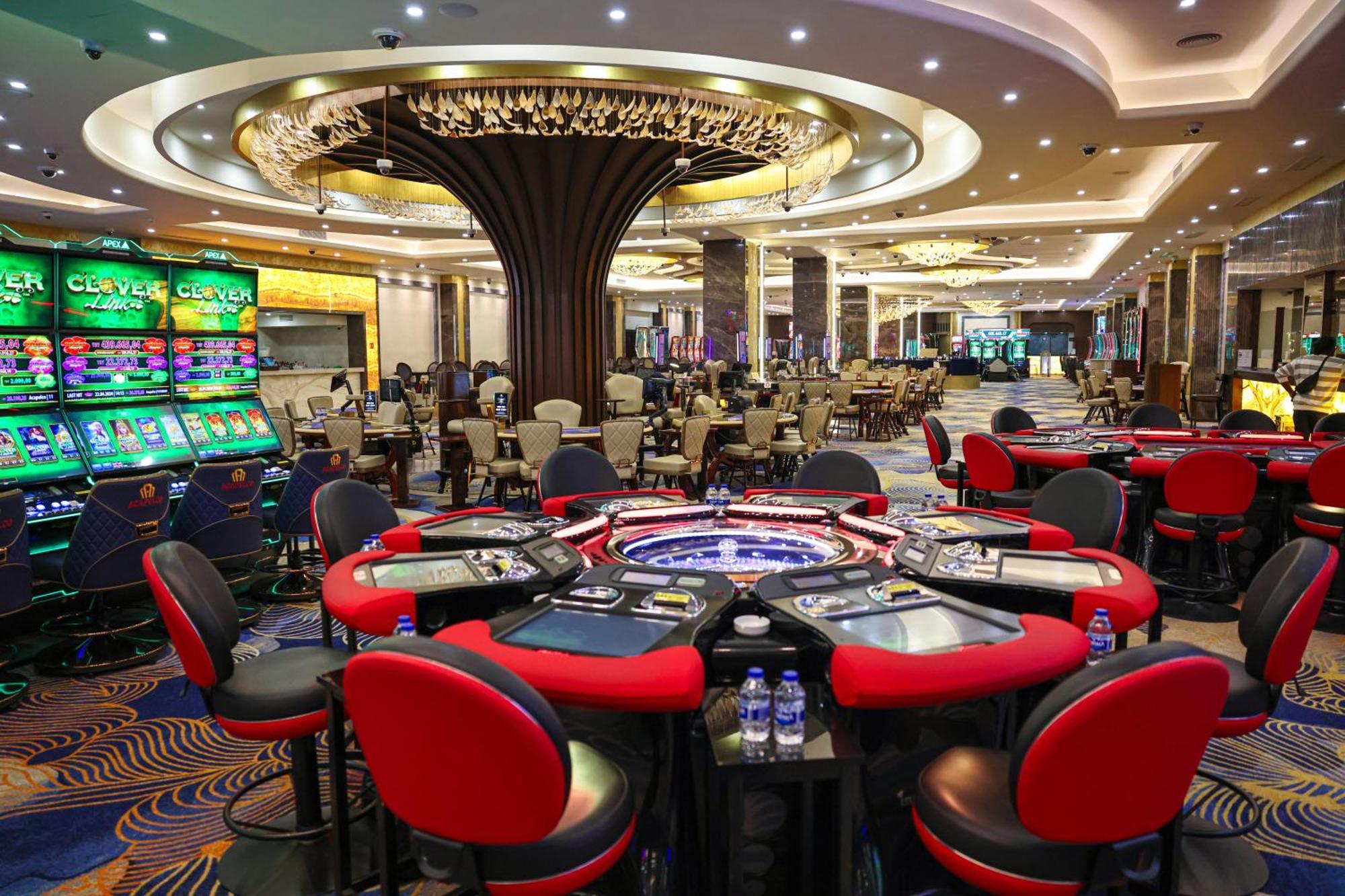 Acapulco Resort Hotel Agios Epiktitos Dış mekan fotoğraf The photo depicts an elegant and modern casino interior. It features several gaming tables, each equipped with red and black seating. In the background, there are slot machines illuminated with colorful lights. The design of the space includes a larg