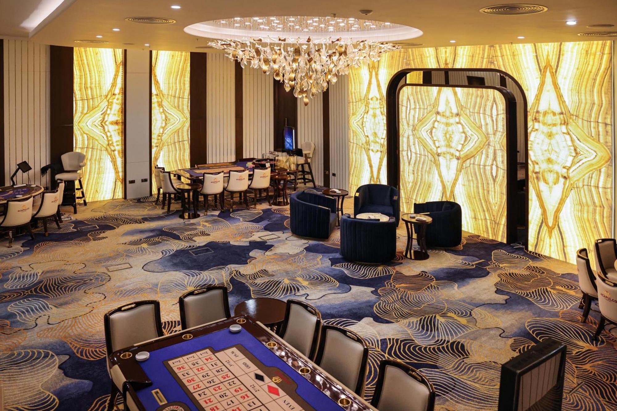 Acapulco Resort Hotel Agios Epiktitos Dış mekan fotoğraf The photo depicts an interior of a casino or gaming room. The space features an elegant design with a large chandelier hanging from the ceiling. There are decorative walls that exhibit a bright, patterned design with yellow tones. 

In the center of 