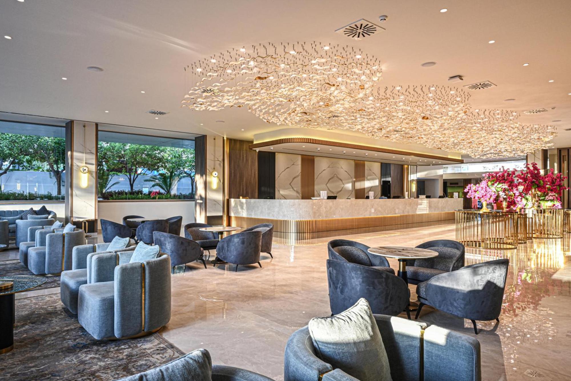 Acapulco Resort Hotel Agios Epiktitos Dış mekan fotoğraf The photo depicts a modern and elegantly designed hotel lobby. It features a spacious area with a sleek reception desk in the background, which has a contemporary design. The ceiling is adorned with a unique chandelier, providing warm lighting. There